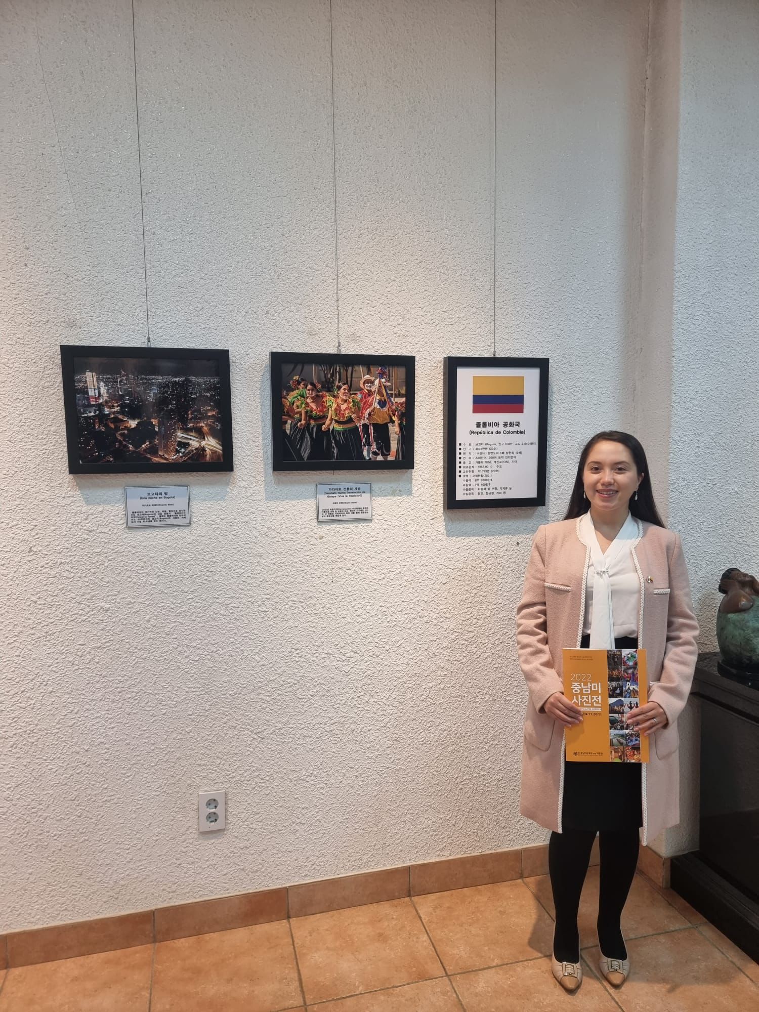 Luz Angela Carrillo, Cónsul y Segundo secretario (Asuntos Culturales) de la Embajada de Colombia en Corea junto a las fotografías “Garabato Nuestra Generación de Galapa ¡Viva la Tradición!” de Sugey Ojeda y “Una noche en Bogotá” de Ricardo Báez.